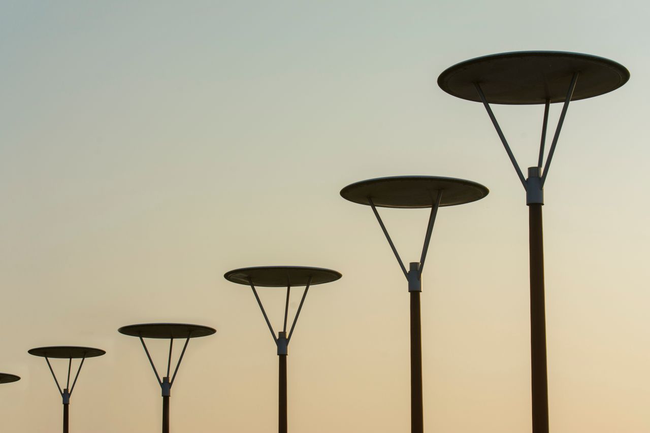 A row of modern street lamps silhouetted against the dusk sky in Zoetermeer, Netherlands.